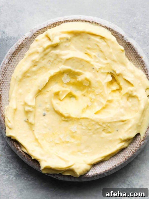A bowl of creamy homemade garlic aioli with flaky salt on top.