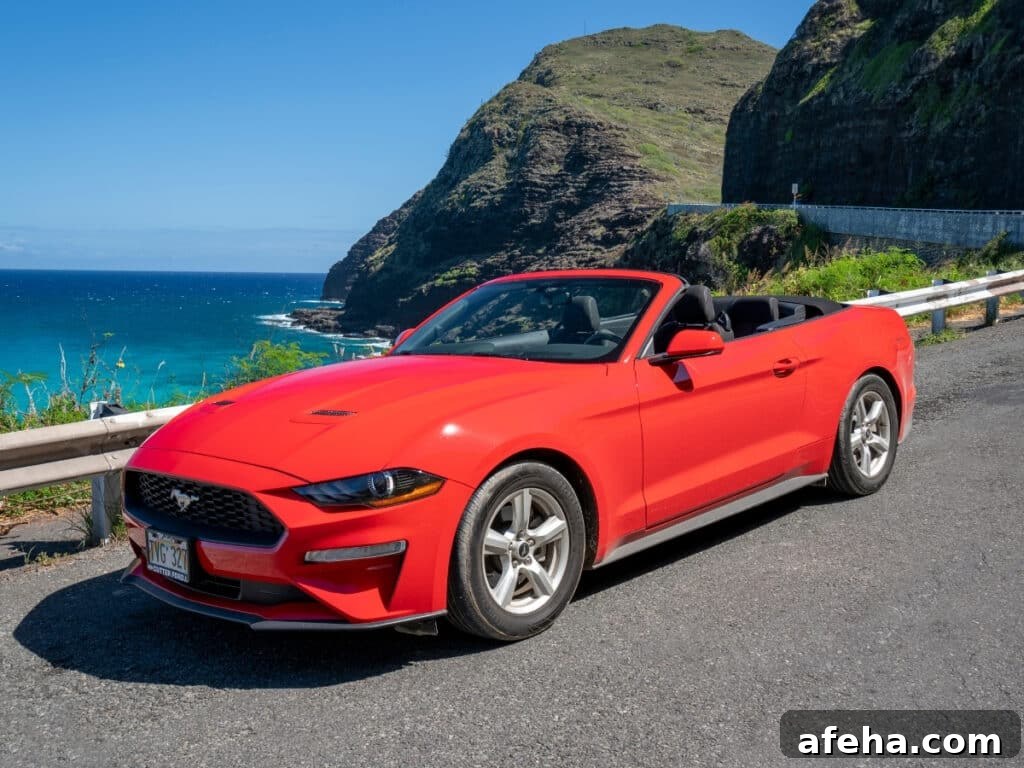 A red convertible rental car on the coastal roads of Oʻahu, Hawaiʻi.