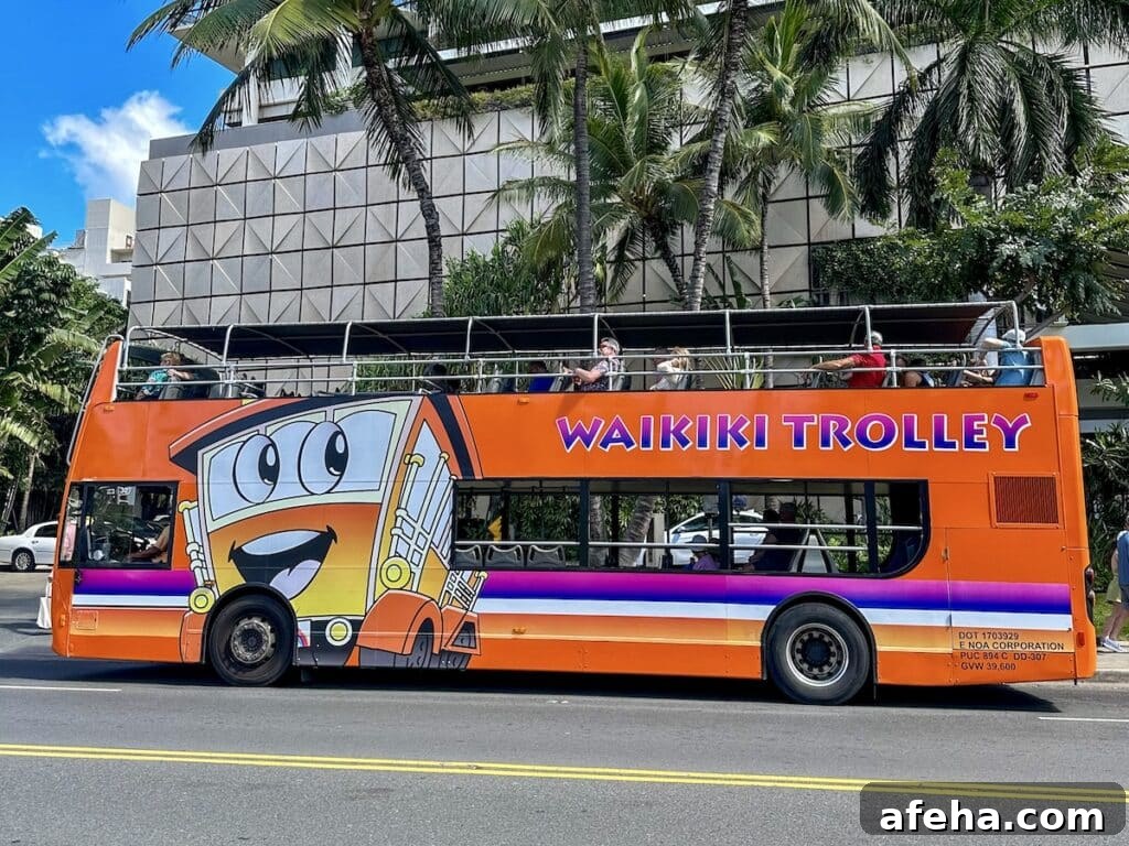 The bright orange Waikīkī Trolley double-decker bus driving in a sunny Waikīkī, Hawai'i.