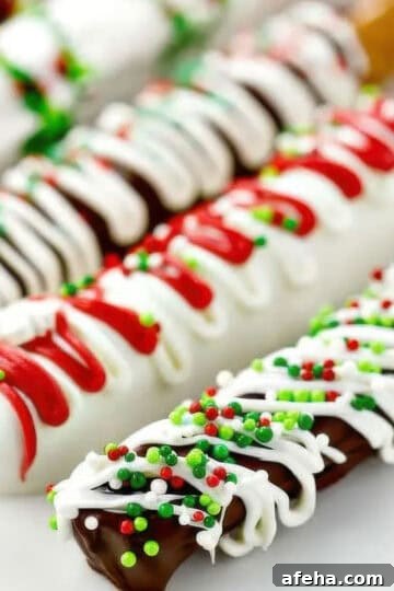 A side view of five chocolate covered pretzel rods decorated with different colors and sprinkles for Christmas