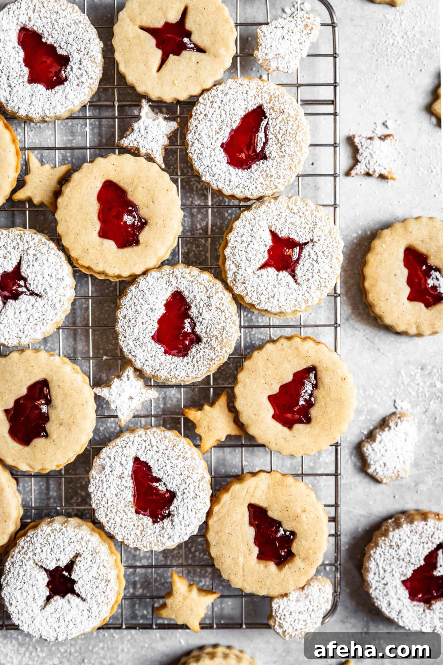 Strawberry Cardamom Linzer Cookies dusted with powdered sugar on top of a wire cooling rack