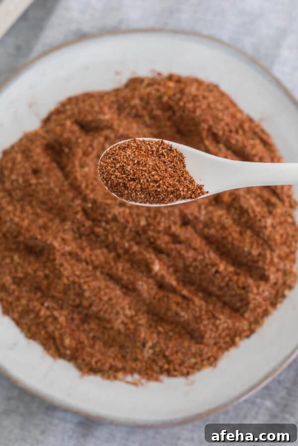 Overhead photo of homemade taco seasoning on a white plate with a spoonful of the seasoning close up.