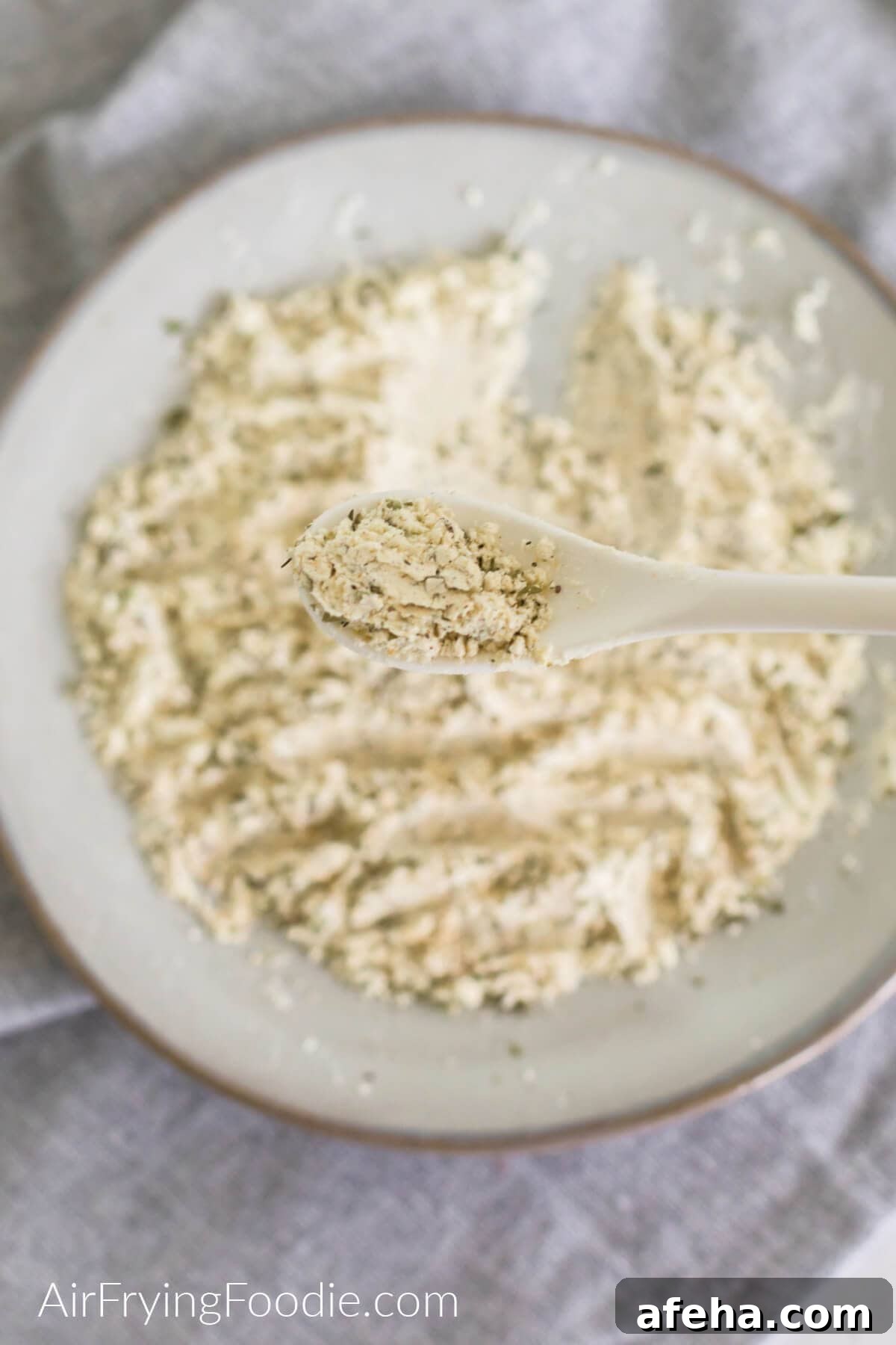 Spoonful of homemade Ranch seasoning with the bowl of homemade Ranch seasoning below.