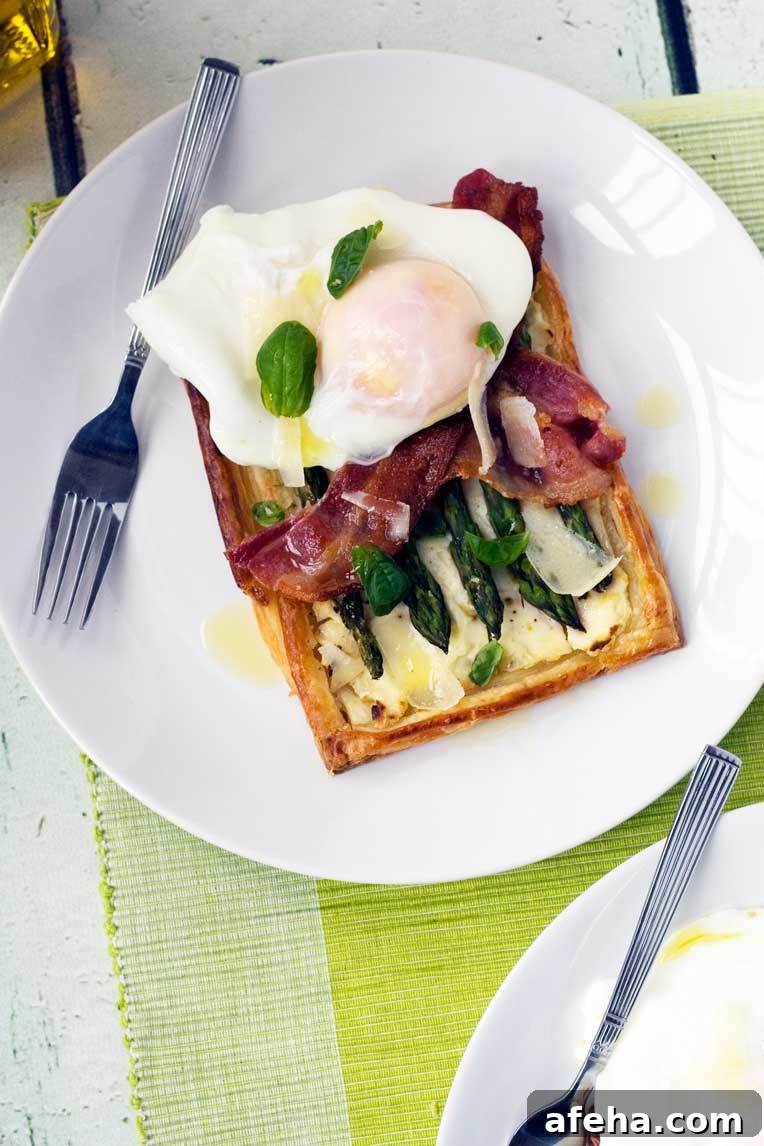 asparagus brunch tart with parmesan and basil with an egg on it on a white plate with a fork and on a green place mat.