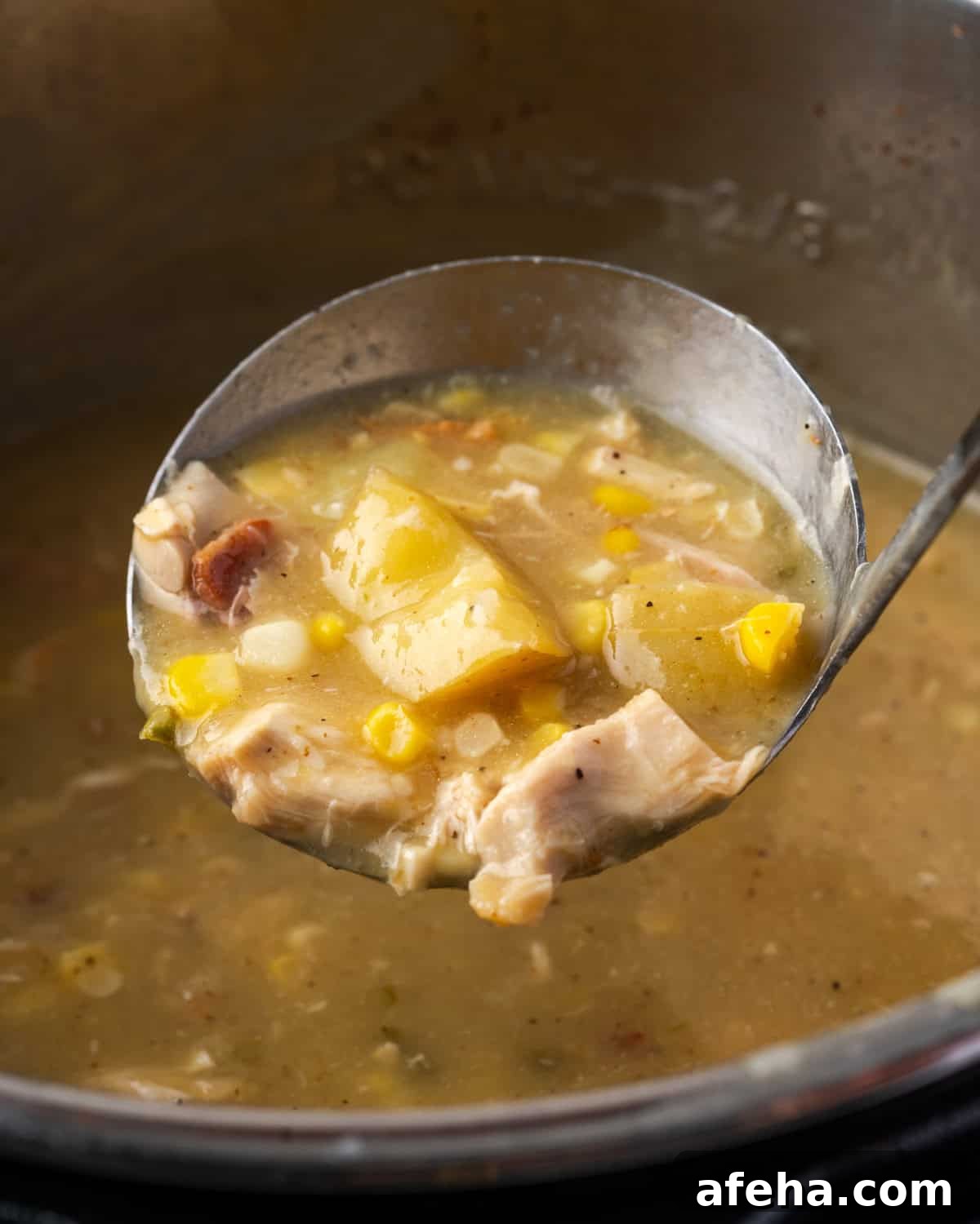 A ladle scooping a serving of chicken corn chowder from the instant pot.