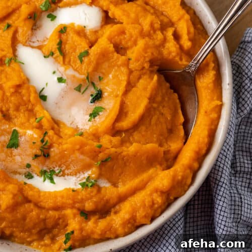 A bowl of mashed sweet potatoes topped with melted butter.