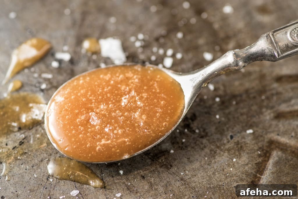 A spoonful of amber colored caramel sprinkled with corse salt on a rustic pie tin.