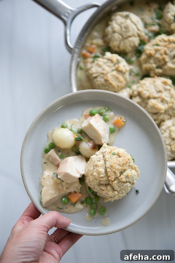 hand holding a plate of gluten-free dairy-free chicken pot pie with GF biscuit topping