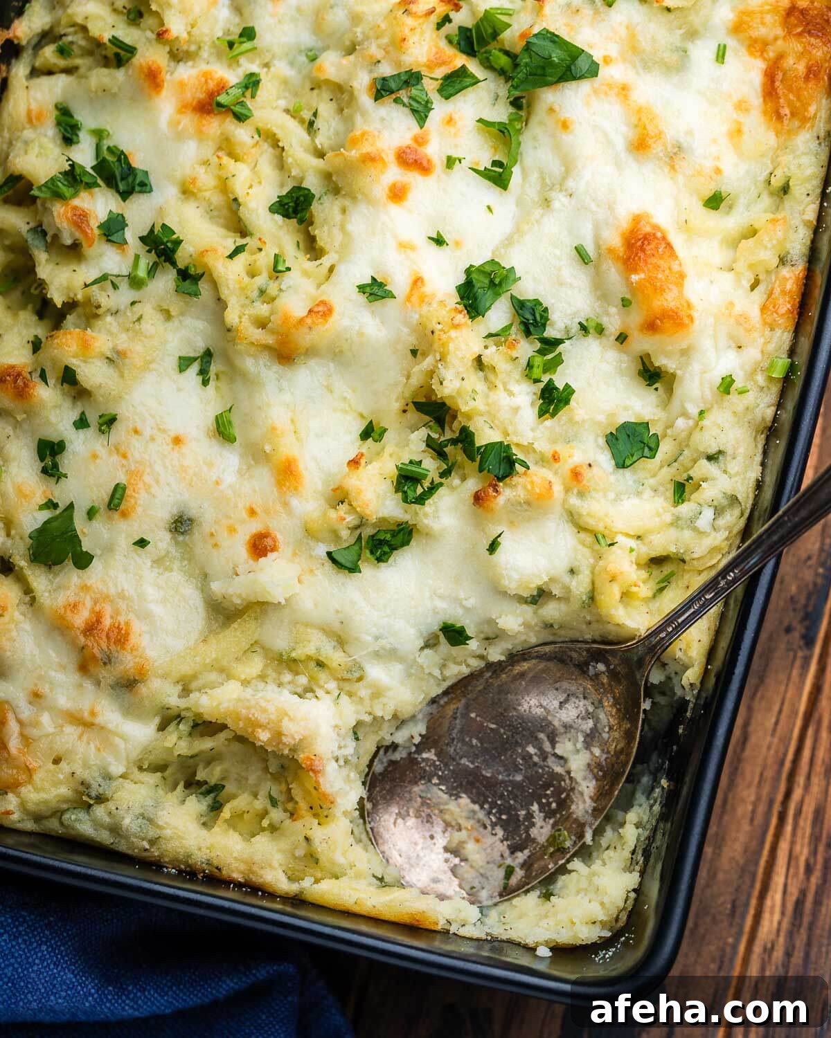 Baking dish with Italian baked mashed potatoes and spoon.