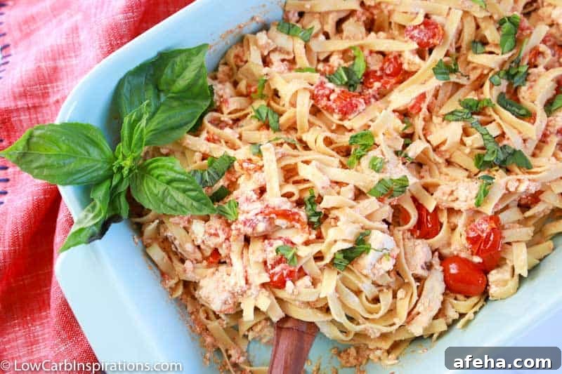 close up photo of baked feta pasta mixed together in a casserole dish with a serving spoon in the bowl