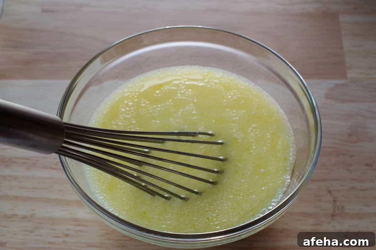 milk, egg yolks and vegetable oil in a glass bowl, being whisked together