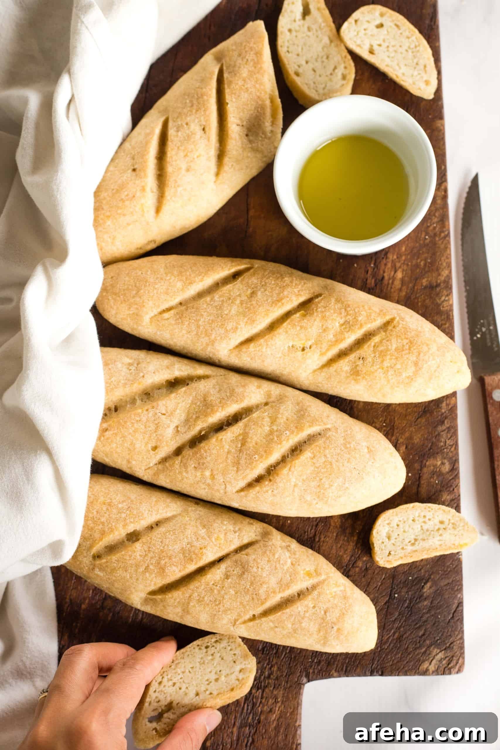 Reaching for a slice of gluten-free baguette on wooden board.