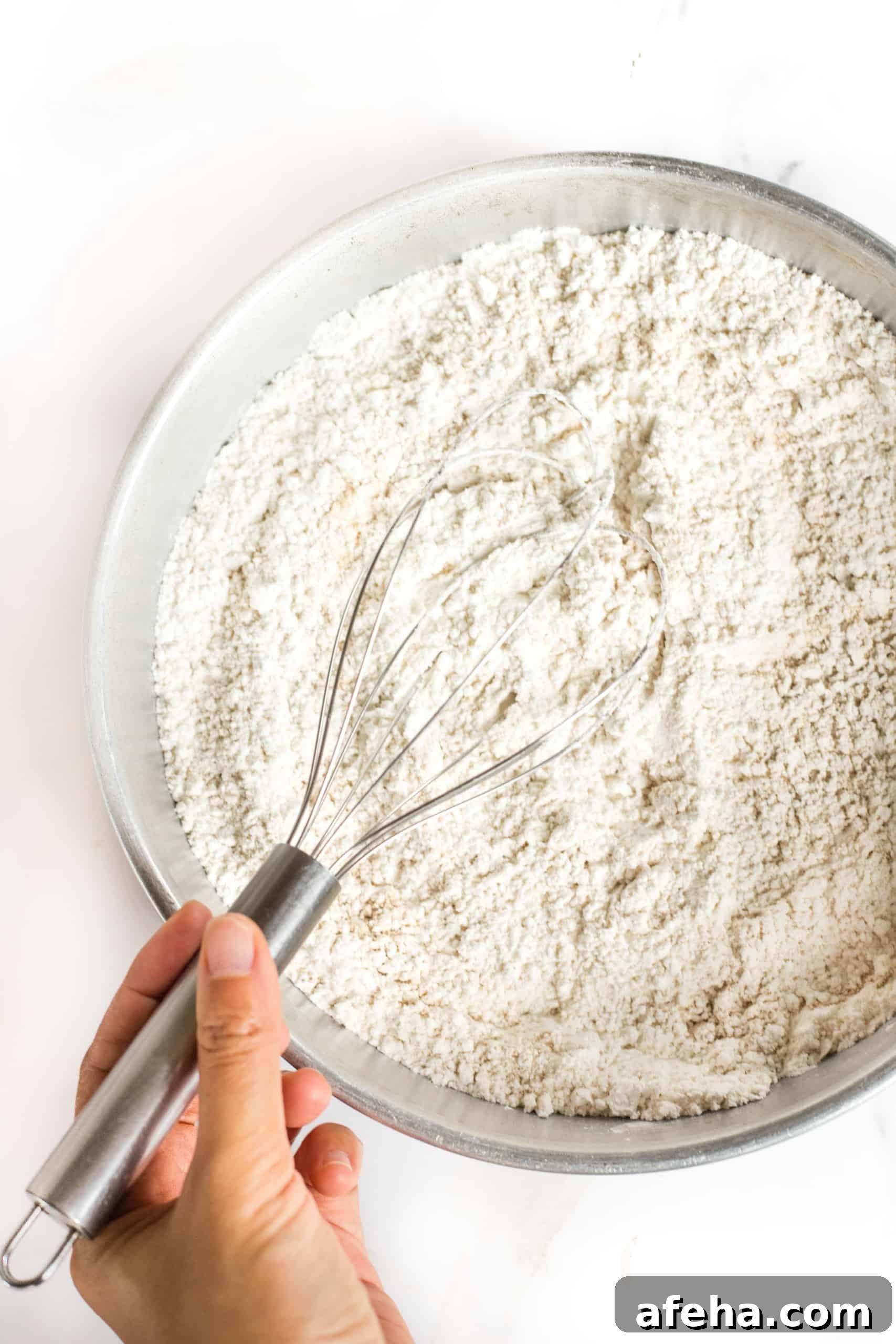 Whisking flour mixture in metal bowl.