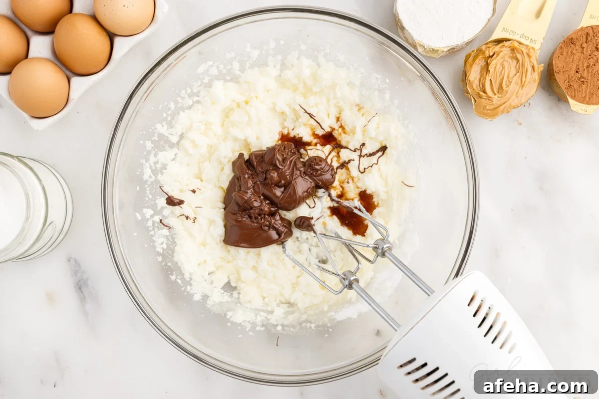 vanilla and melted chocolate added to butter mixture in mixing bowl with hand mixer to make peanut butter brownies