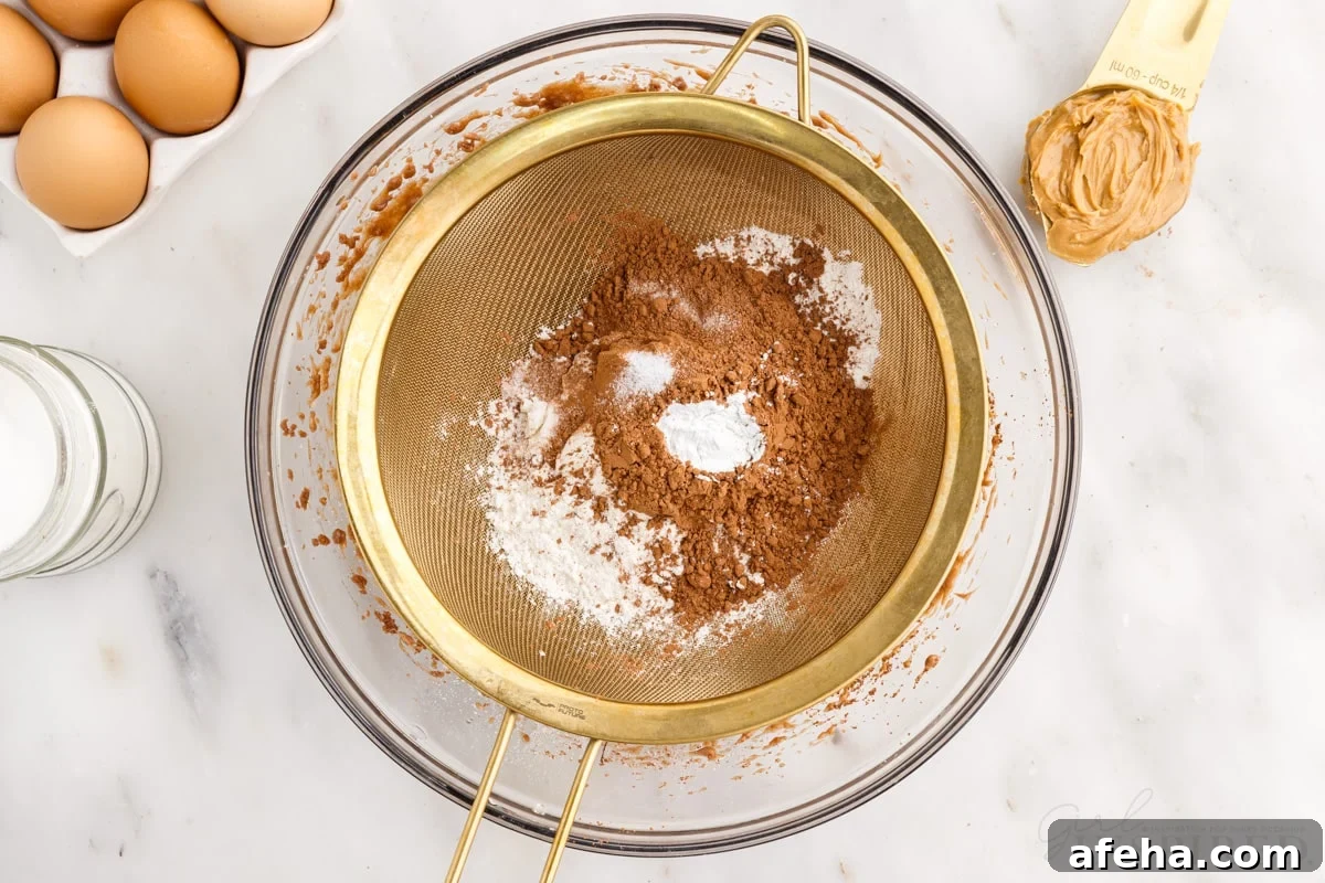 brownie batter, cocoa powder and flour in a sieve over wet ingredients