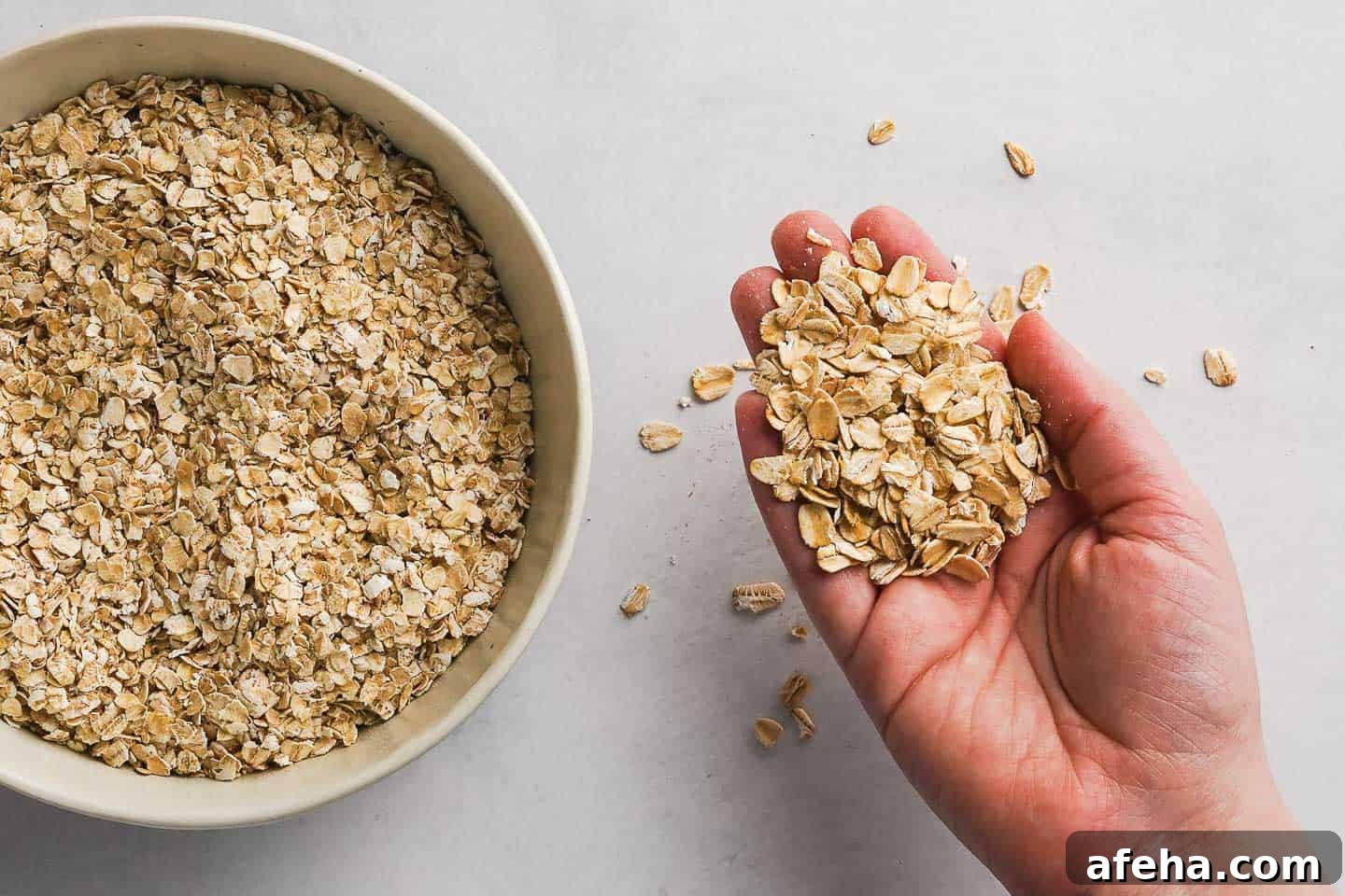 Bowl of quick oats next to hand holding old-fashioned rolled oats