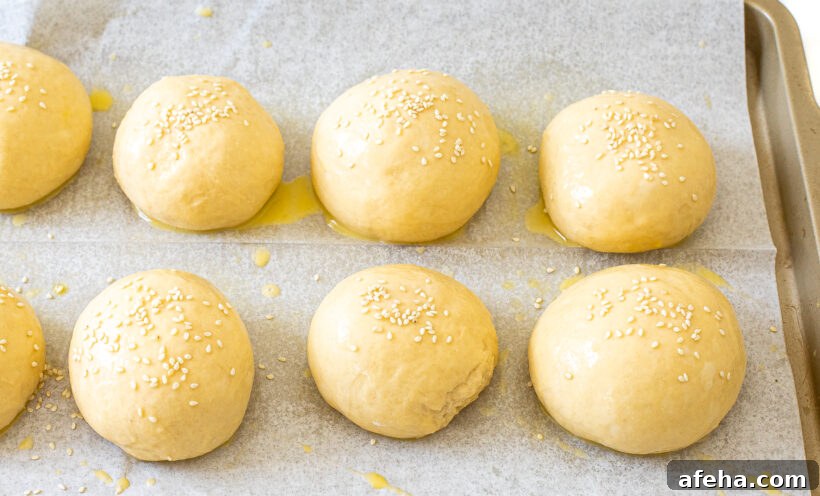 unbaked burger buns on baking sheet