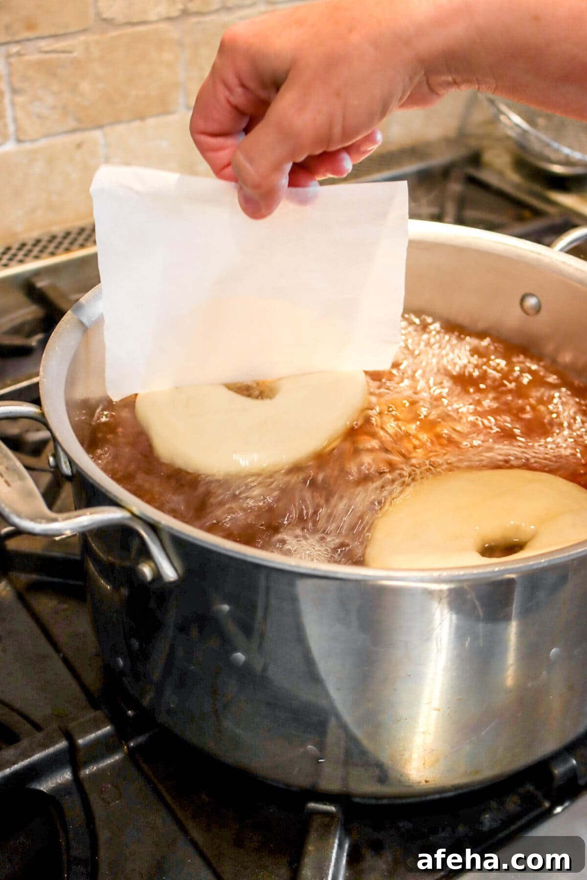 bagel being placed into stock pot