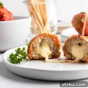 Mozzarella stuffed turkey meatballs on plate with cheese stretching.