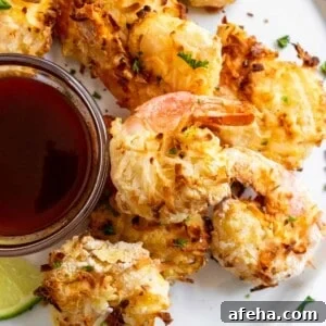 Coconut shrimp on white plate with sauce.