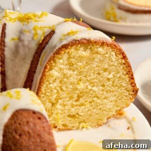 Lemon bundt cake on cake plate with slice cut out to show texture of cake.