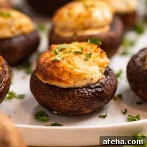 Air fried stuffed mushrooms on white plate topped with chopped parsley.