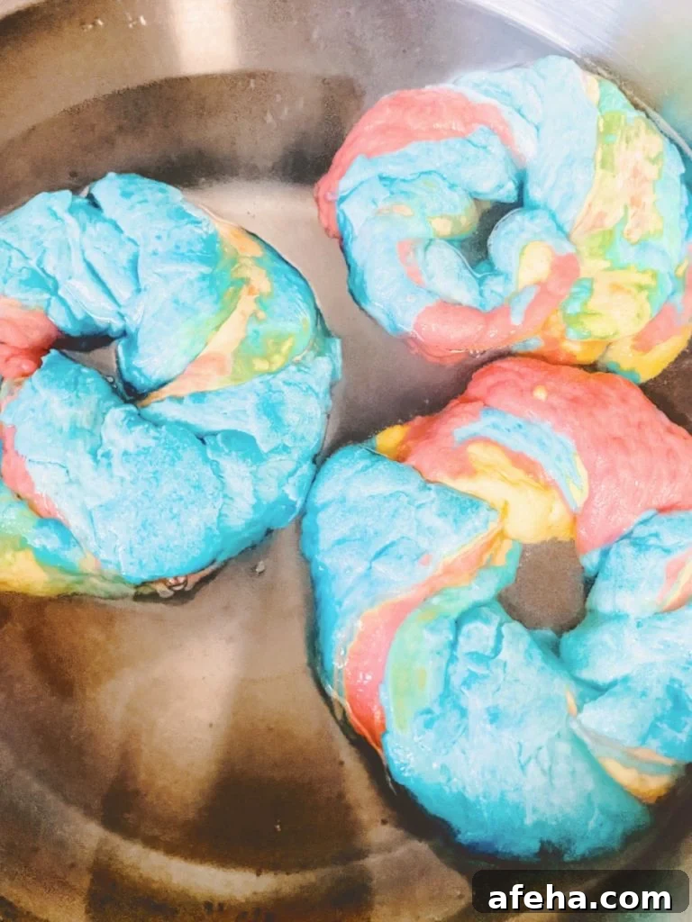 three rainbow bagels boiling in a pot of water