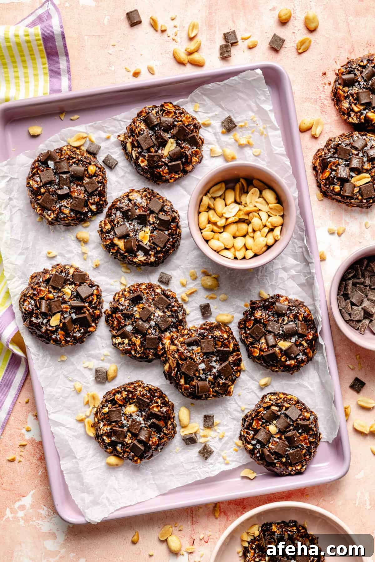 a tray of no-bake chocolate oat cookies and salted peanuts on a light pink background