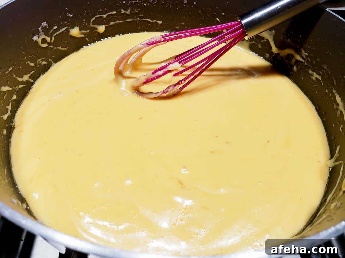 Creamy Cheddar Vegetable Soup Recipe for Cozy Weeknights 9 cheese melted into milk mixture in a pan.