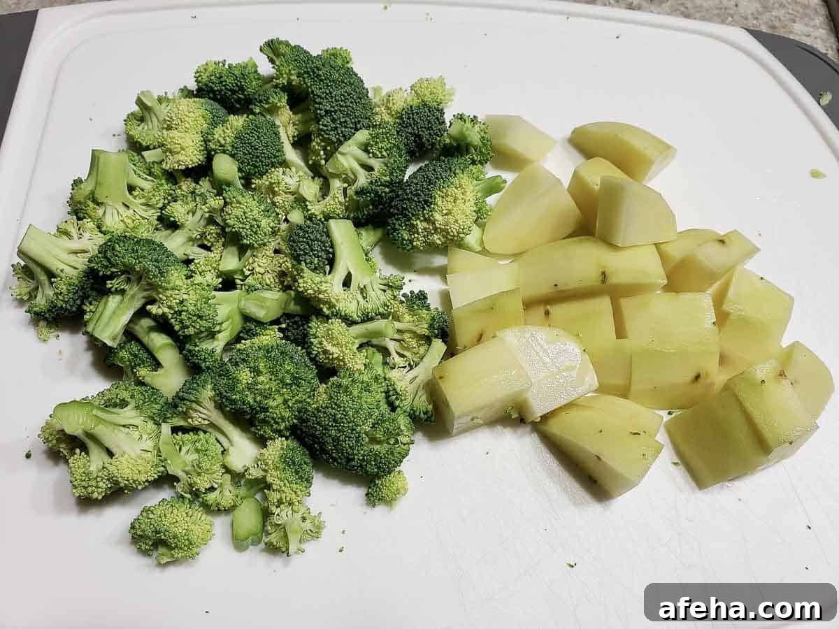 Creamy Cheddar Vegetable Soup Recipe for Cozy Weeknights 3 chopped potatoes and broccoli on a cutting board.