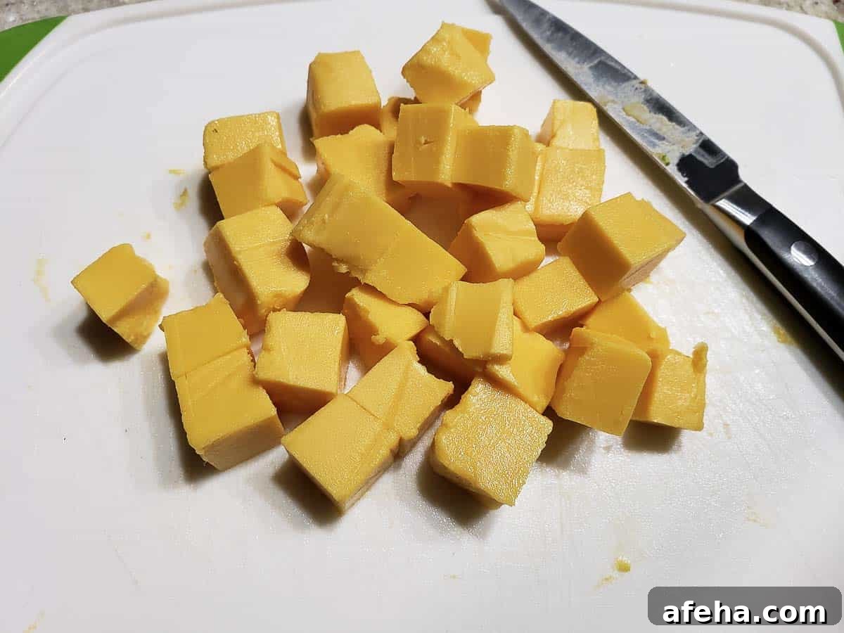 Creamy Cheddar Vegetable Soup Recipe for Cozy Weeknights 4 cubed velveeta cheese on a cutting board.