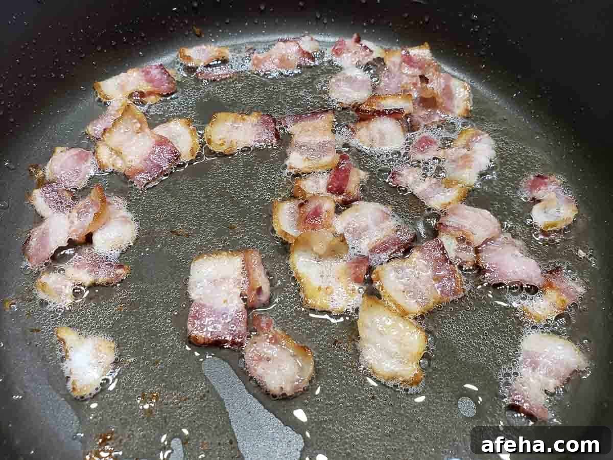 Creamy Cheddar Vegetable Soup Recipe for Cozy Weeknights 5 1 inch pieces of bacon frying in a pan.