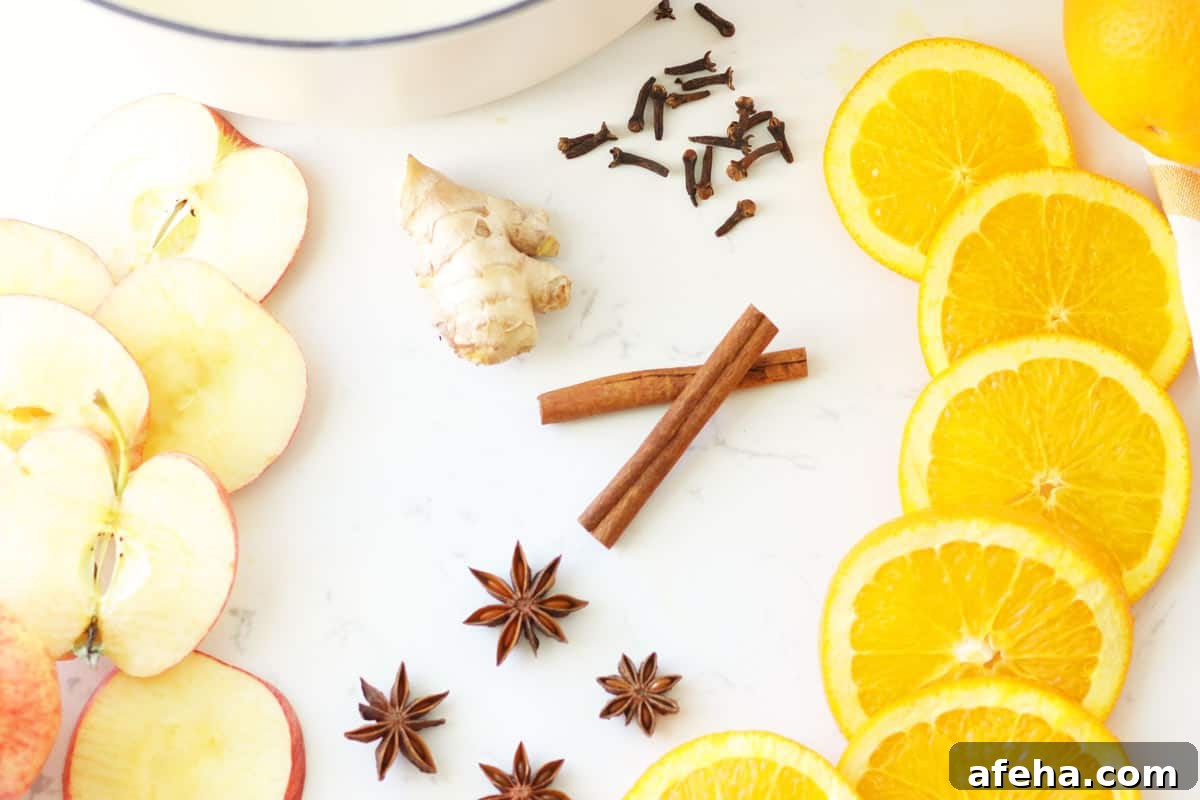 sliced oranges and apples, cinnamon ticks, ginger root, star anise and whole cloves laying next to a dutch oven.