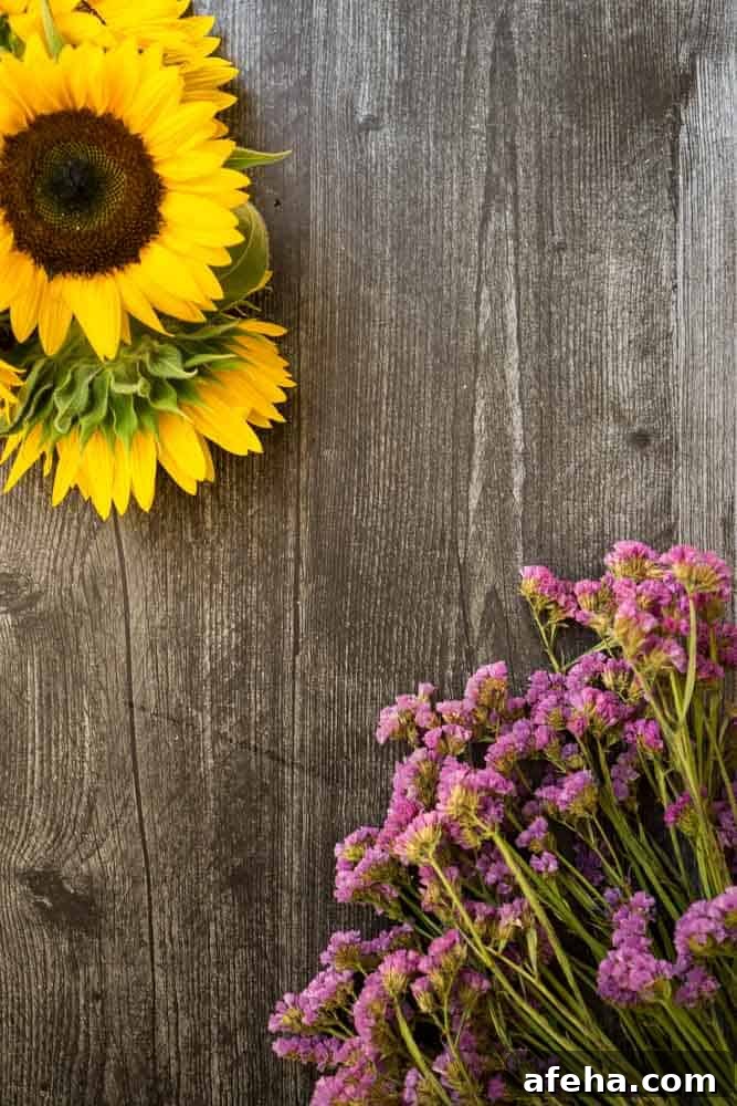 orange "excel" sunflower and blue statice on dark wooden background