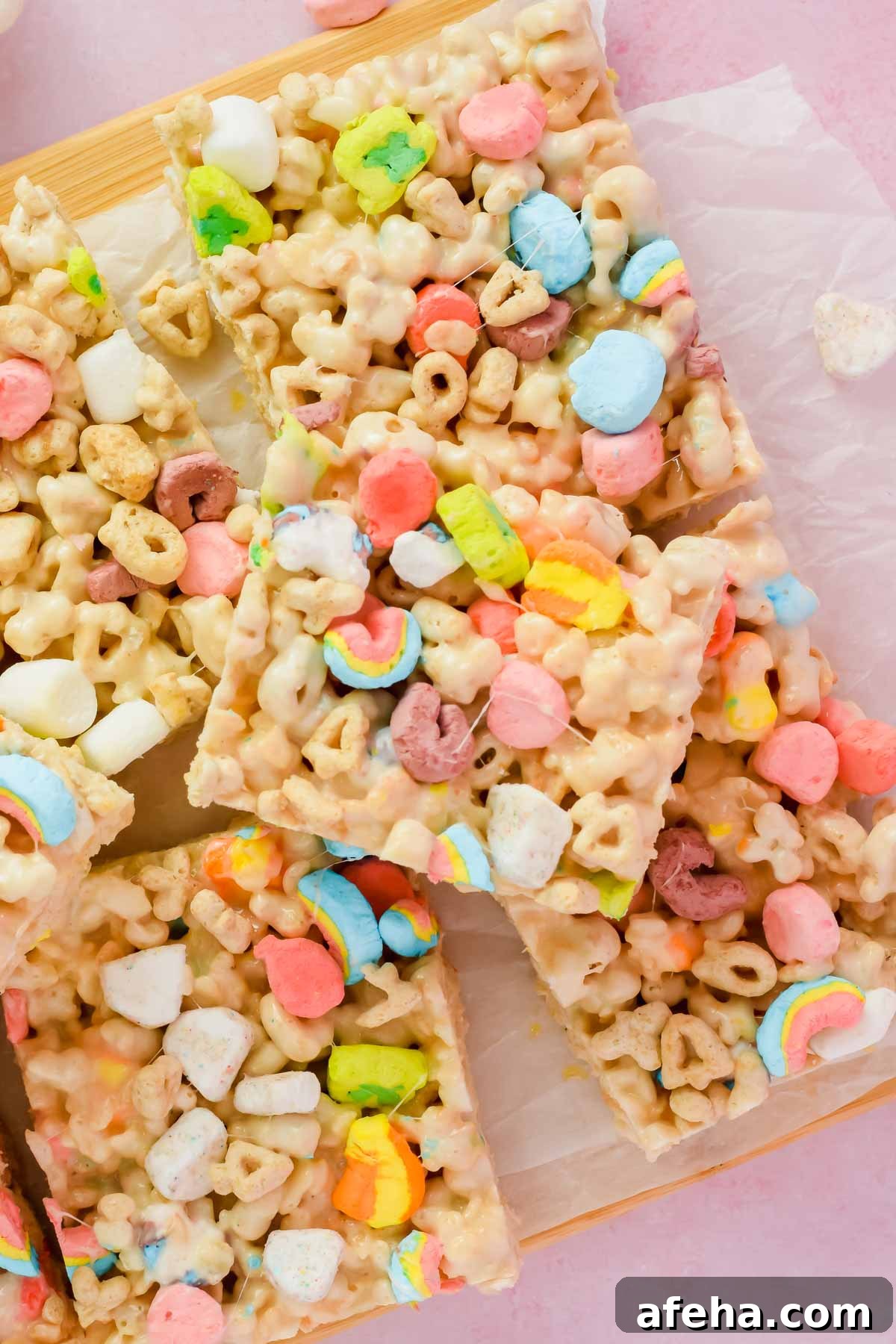 stacked lucky charm rice krispie treats cut into squares on white parchment.