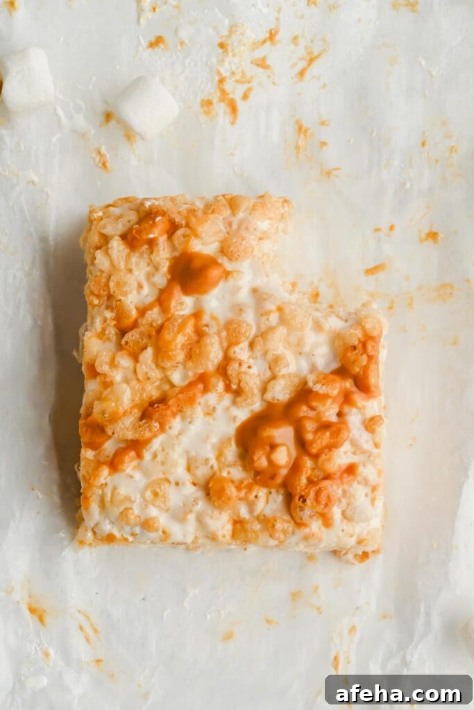 one marshmallow fluff rice krispie treat with bite taken out of it on white parchment.