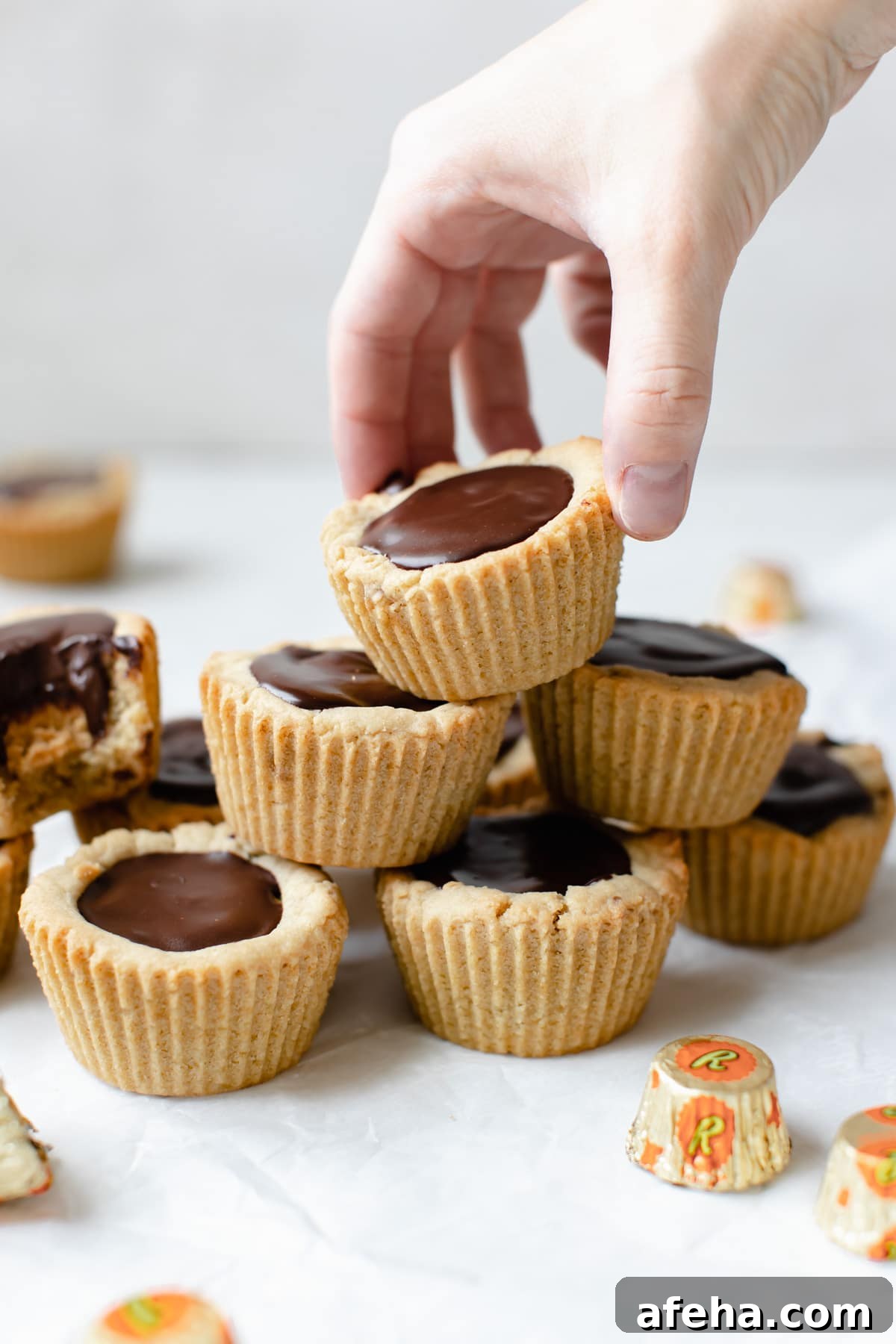 a woman's hand picking up a peanut butter cup cookie