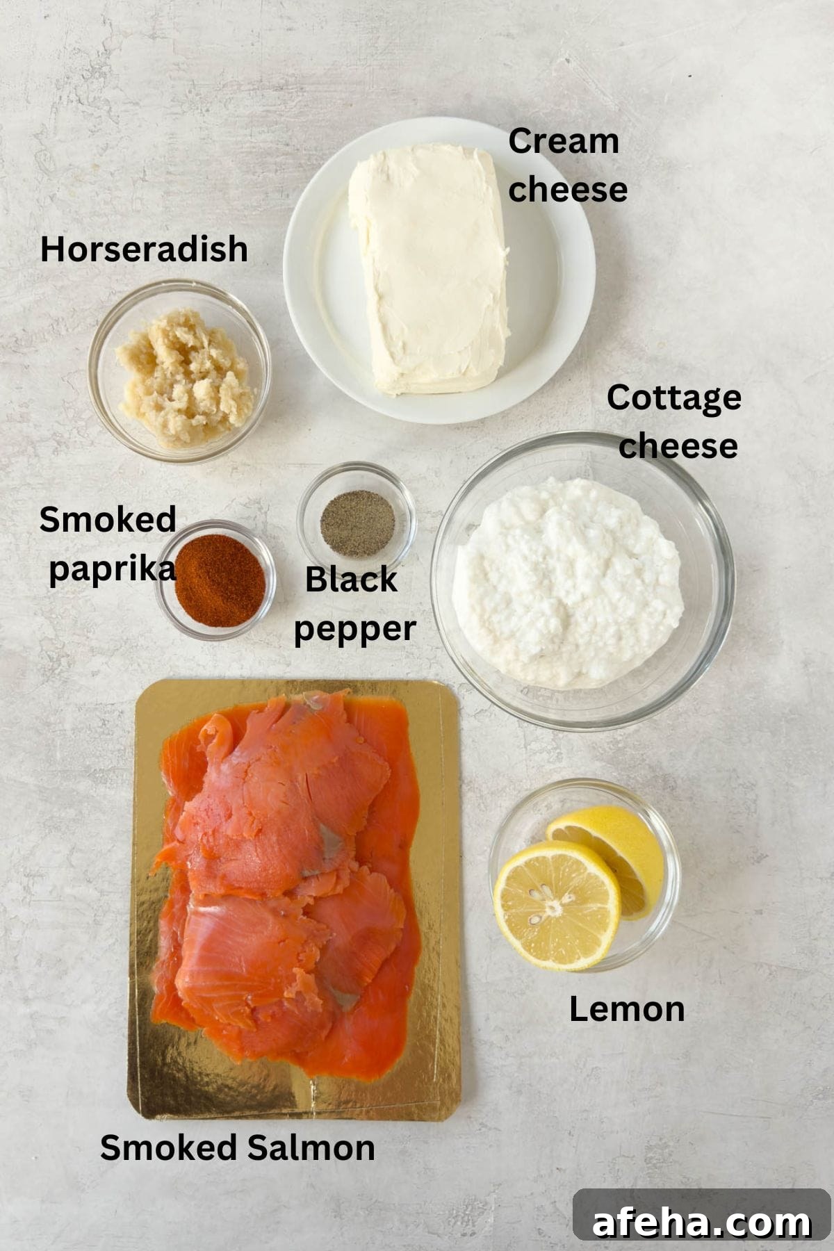 Ingredients for smoked salmon dip in glass prep bowls on a gray counter.
