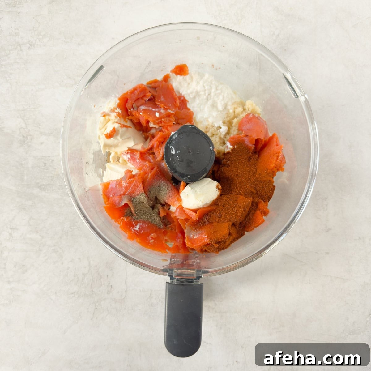Smoked salmon, cottage and cream cheeses, spices, and horseradish in a food processor workbowl.