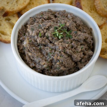 Closeup of mushroom pate in a white ramekin with a spoon.