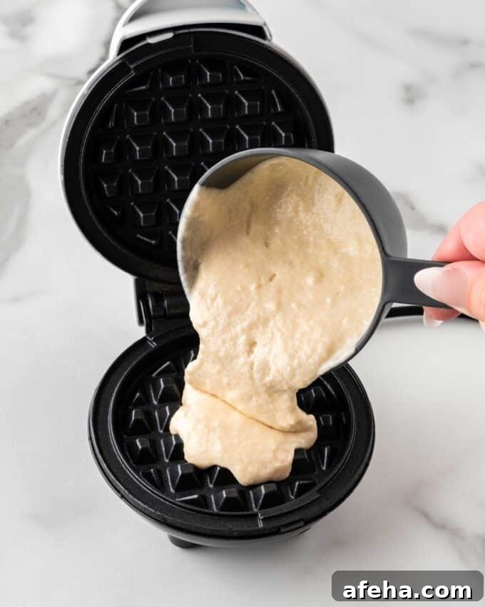 pouring waffle batter in mini dash waffle maker