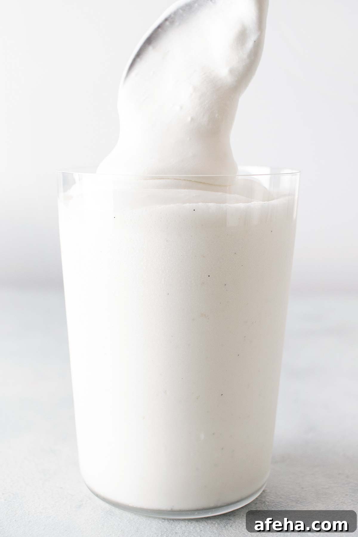 Spooning whipped cream on top of a Frappuccino.