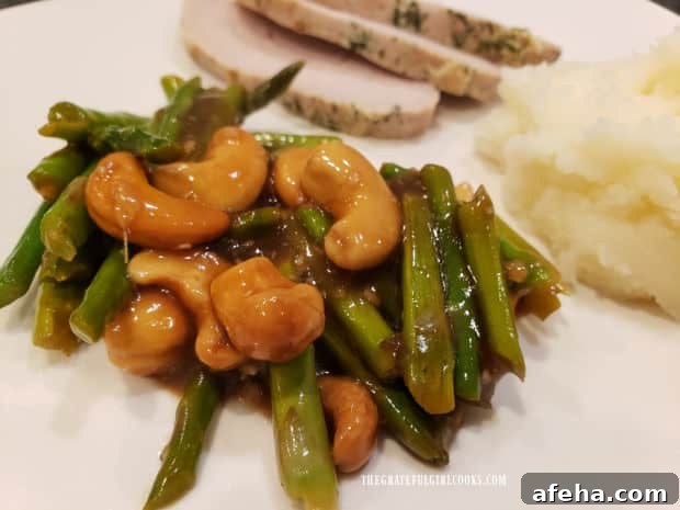 Sliced pork loin and mashed potatoes are served with the asparagus cashew stir fry.
