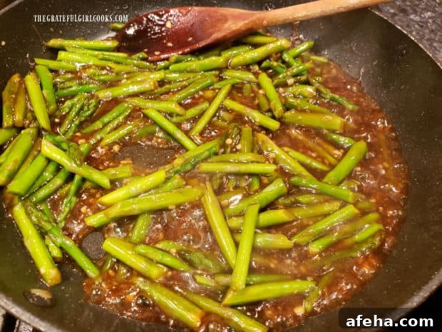 The stir fry sauce has thickened in the skillet with the asparagus.