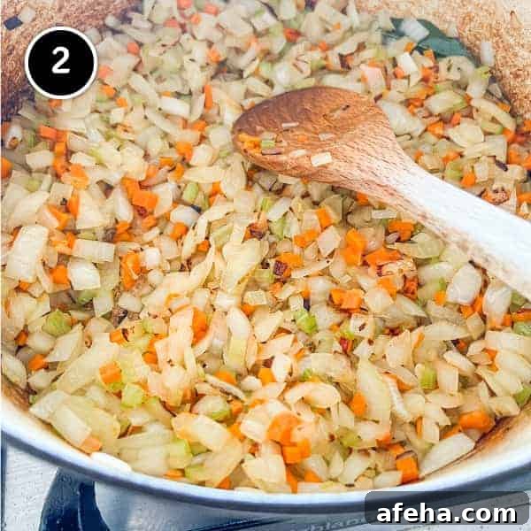 Onions, celery and carrot frying in a pan with bay leaves.