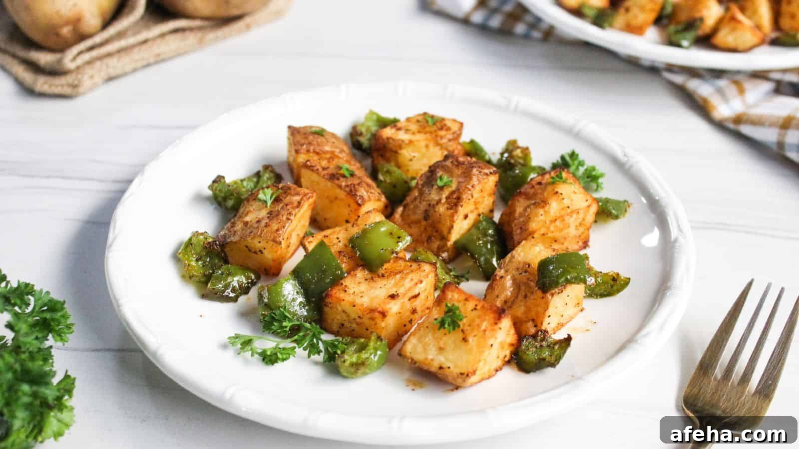 Air-fried potato cubes with diced green bell peppers on plate.