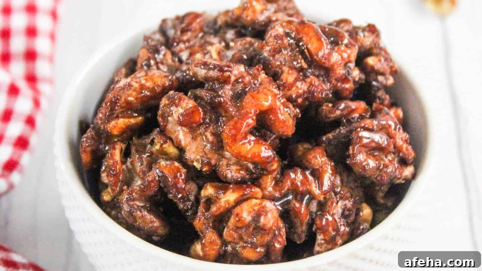 Bowl of glazed candied walnuts on a white surface.