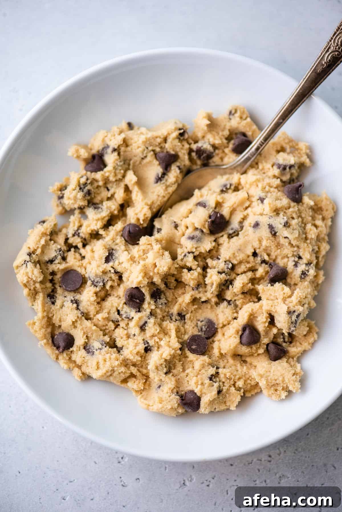 Overhead view of chocolate chip cookie dough in bowl with spoon