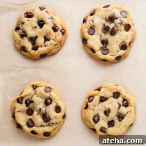 Overhead view of 4 chocolate chip cookies on parchment paper