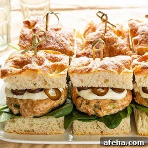 Mediterranean Salmon Slakers: Flavorful Mini Salmon Sliders 2 Mediterranean Style Salmon Sliders on a white platter on a beige tablecloth